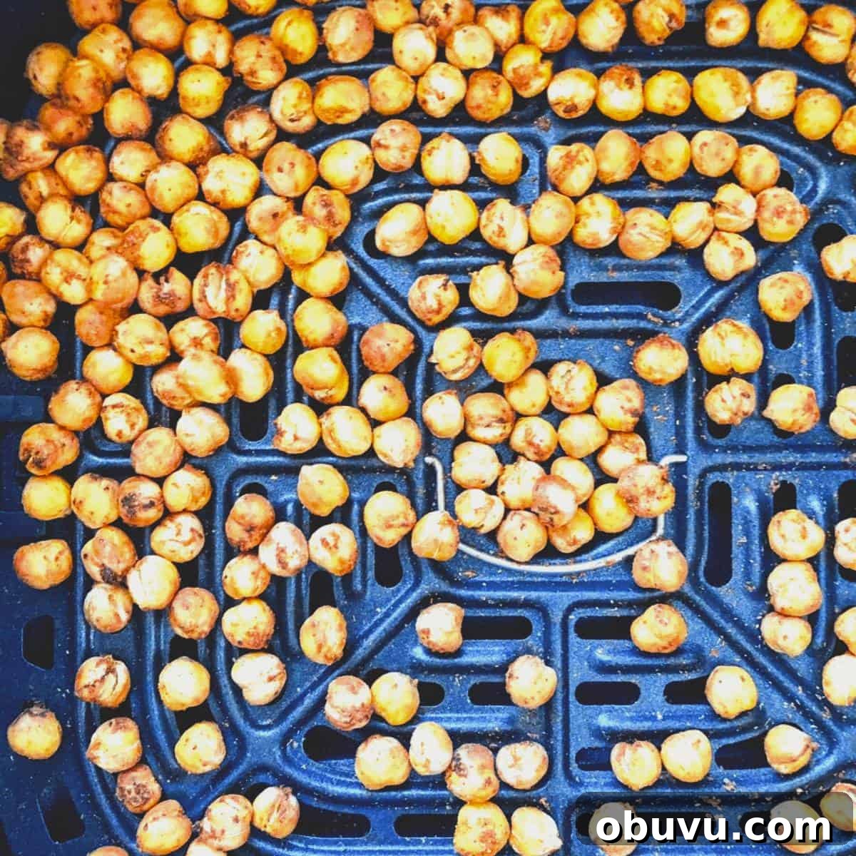 Crispy golden brown cooked chickpeas in the air fryer basket.