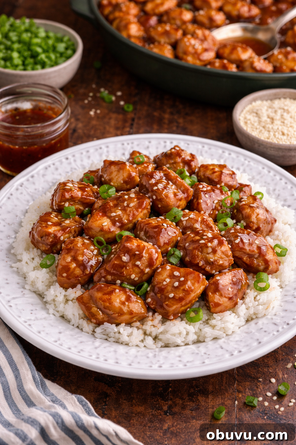 30-Minute Bourbon Chicken Skillet Recipe That Beats Takeout 2 Bourbon Chicken piled on top of a plate with some rice on the side and topped with sesame seeds and green onions