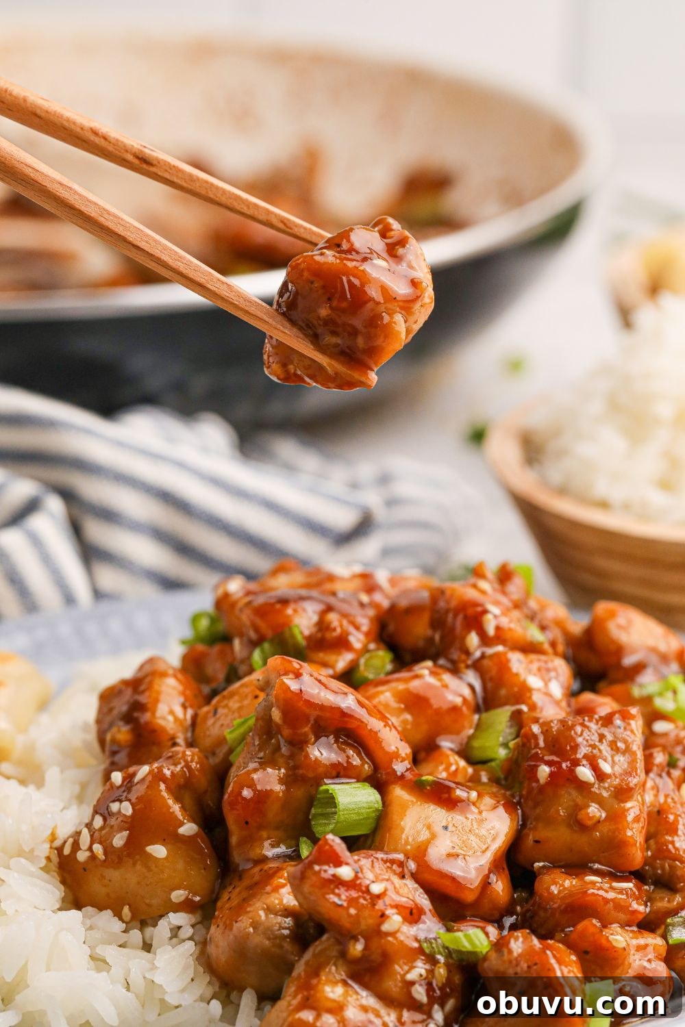 30-Minute Bourbon Chicken Skillet Recipe That Beats Takeout 20 Bourbon Chicken on a plate with some chopsticks lifting a piece of chicken out of the plate