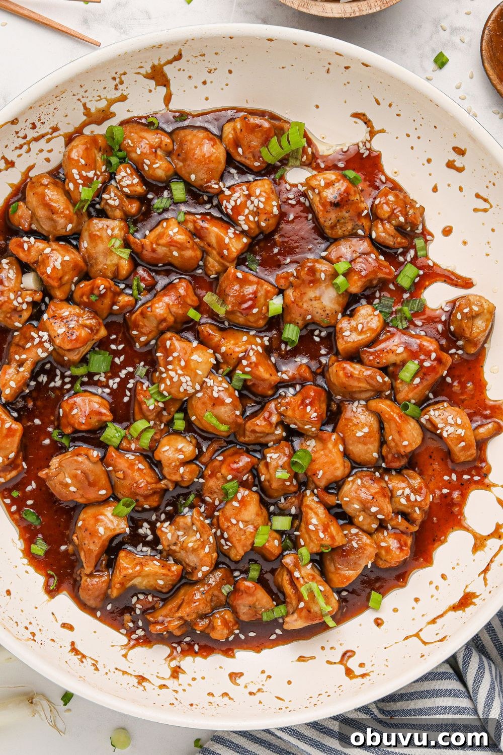 30-Minute Bourbon Chicken Skillet Recipe That Beats Takeout 22 side view of a white skillet on table full of saucy bourbon chicken