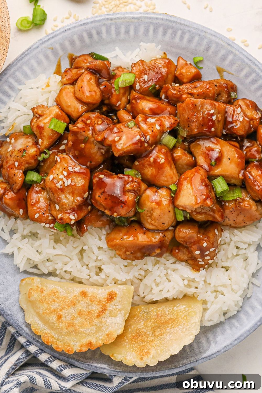 30-Minute Bourbon Chicken Skillet Recipe That Beats Takeout 23 Bourbon Chicken close up on plate with a bit of rice and topped with sesame seeds and green onions on top