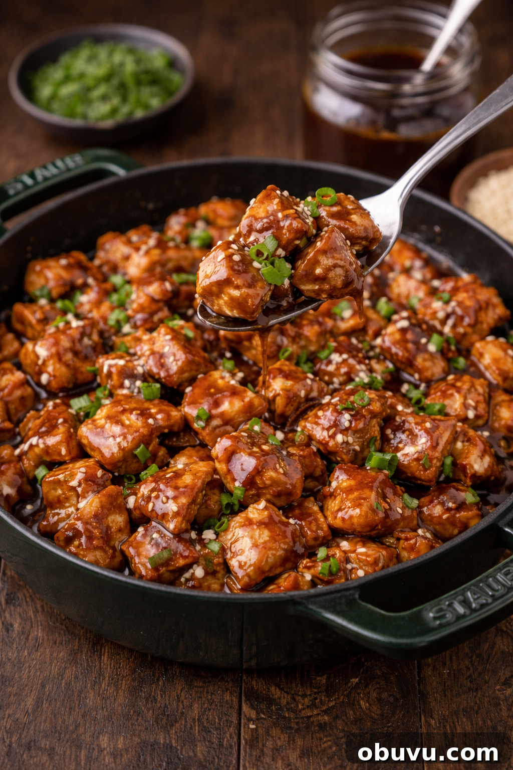 30-Minute Bourbon Chicken Skillet Recipe That Beats Takeout 5 Bourbon Chicken in a green staub skillet with a spoon lifting up a bite
