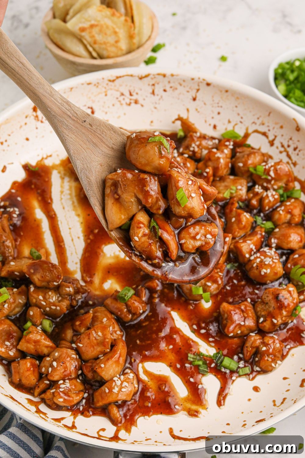 30-Minute Bourbon Chicken Skillet Recipe That Beats Takeout 10 skillet with Bourbon Chicken in it with sauce and a spoon scooping up the chicken