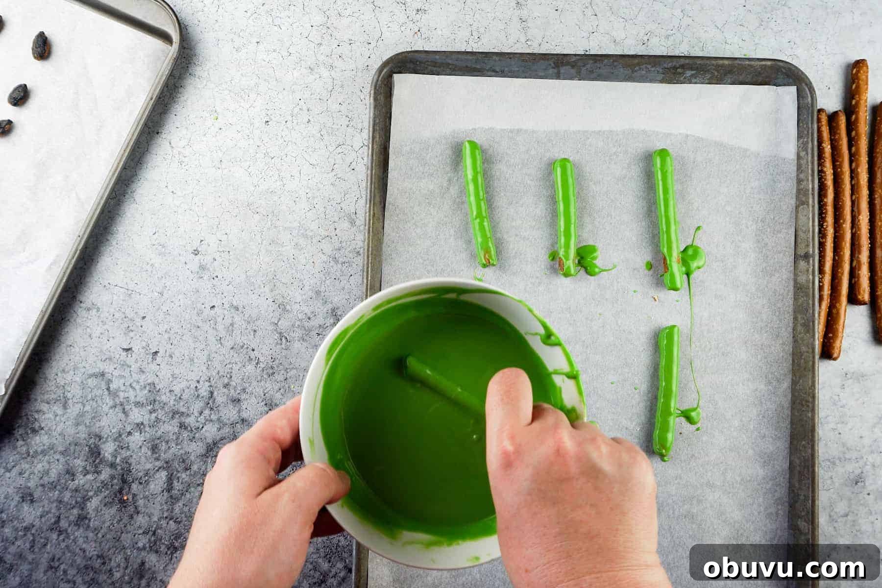 Witch Finger Cookies Recipe: Spooky Halloween Treats 6 coating a pretzel rod in green candy melts.