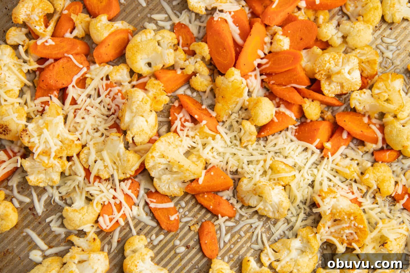 Roasted Carrots and Cauliflower in Cheesy Garlic Crust 8 This is a picture of a baking tray with roasted carrots and cauliflower with cheese added.