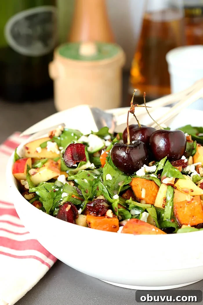 Roasted Sweet Potato & Spinach Chopped Salad with Maple Vinaigrette 4 Sweet Potato and Spinach Salad with Pecans, Cherries and Goat Cheese Served in a White Bowl and Whole Cherries for Garnish