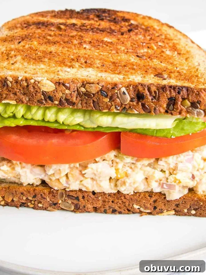 Side view of a vegan tuna sandwich with lettuce and tomatoes on toast.