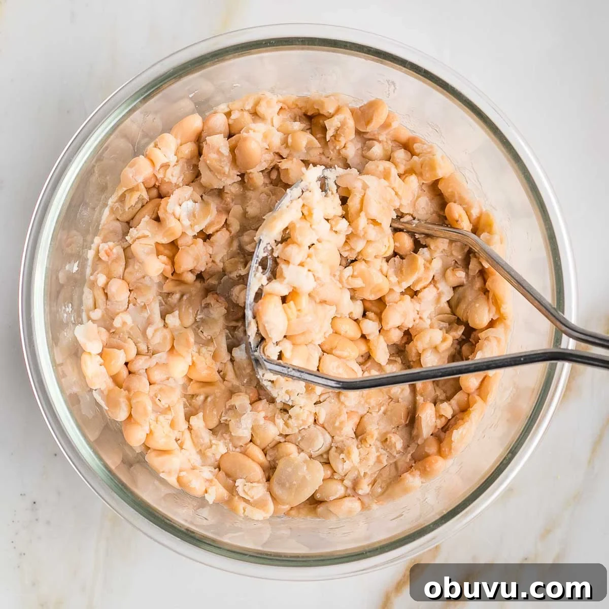 Crispy Vegan Chicken Salad with Creamy Herb Dressing 4 Potato masher mashing cannellini beans in a glass bowl.