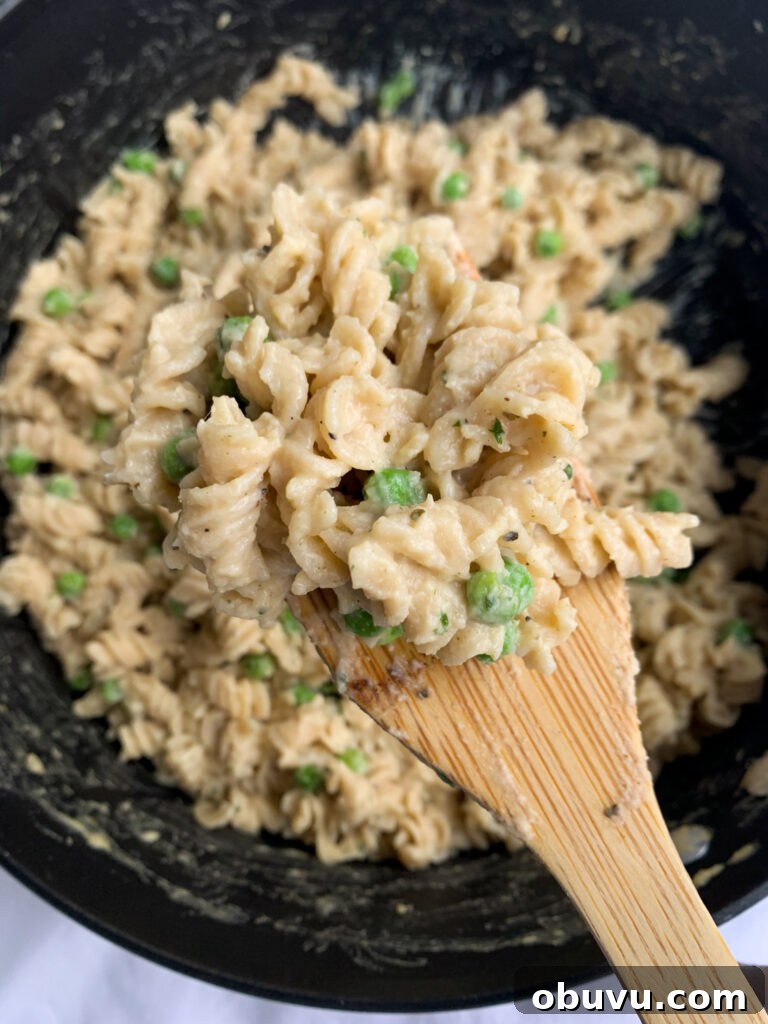 Creamy Cauliflower Pasta: Velvety Sauce & Garlic Parmesan Recipe 2 a pot of creamy cauliflower pasta with a wooden soon holding some of the pasta closer to the camera