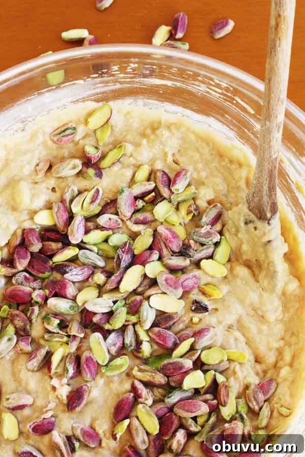 Banana Pistachio Cake with White Chocolate Cream Cheese Frosting 7 Closeup of a bowl of banana cake batter with pistachios sprinkled over the top