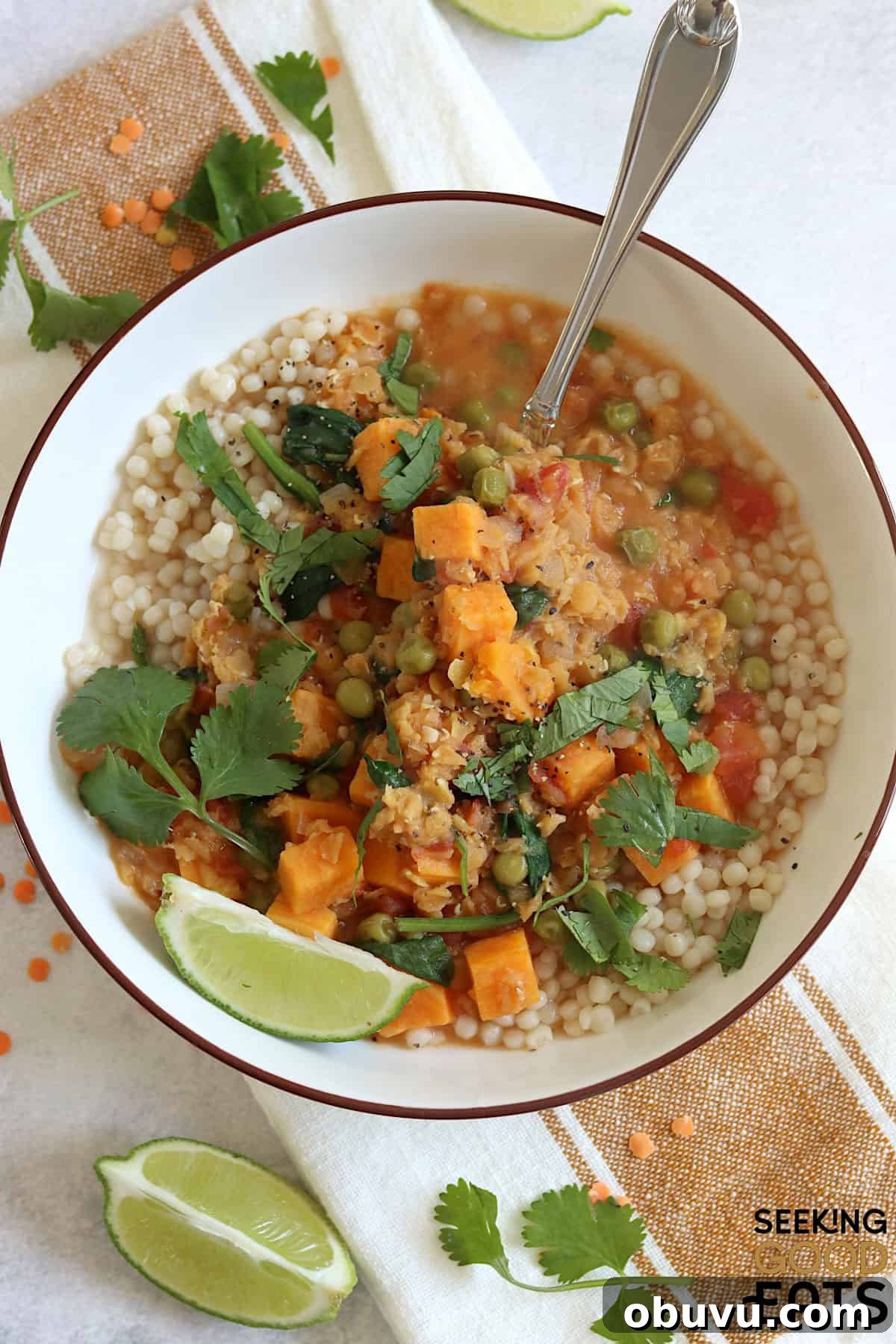A white bowl filled with sweet potato red lentil curry recipe and silver spoon.