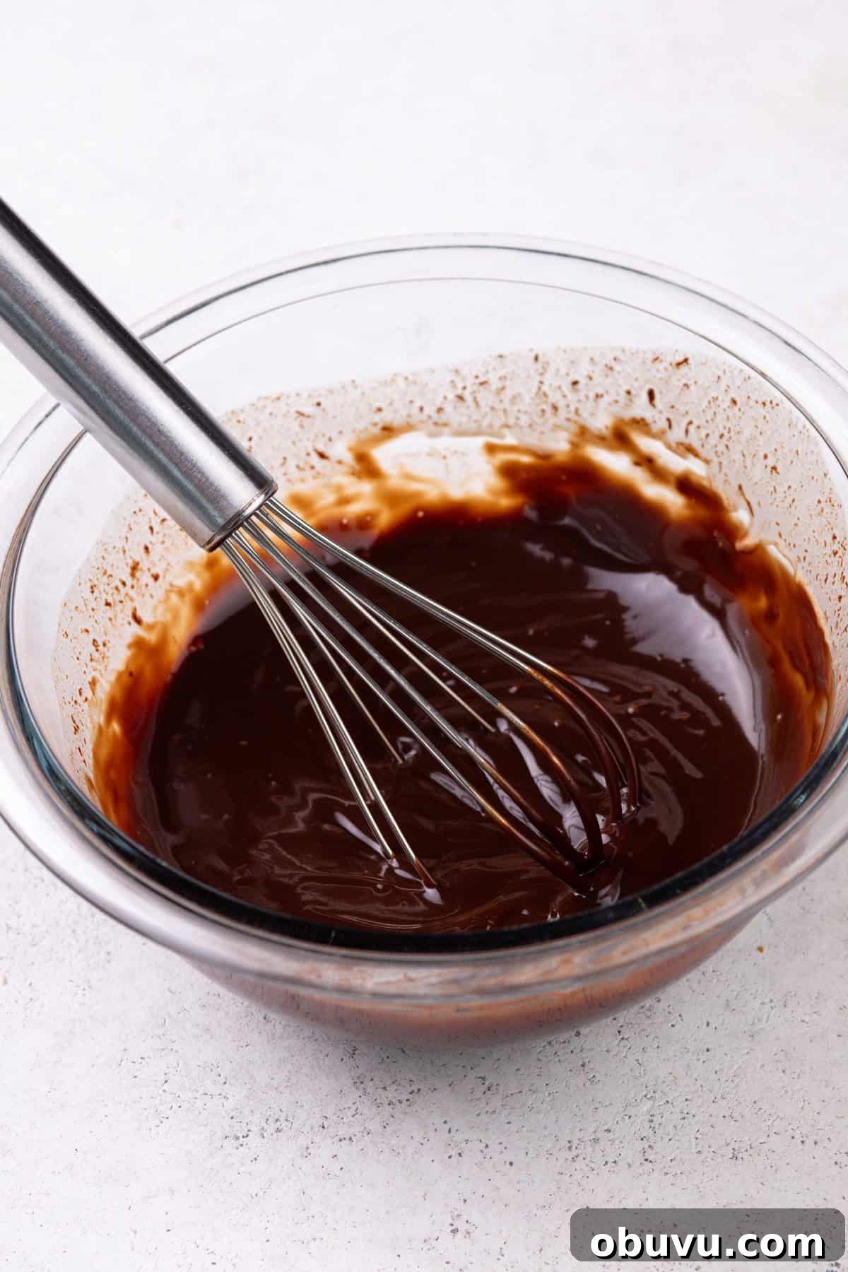 Chocolate ganache in a glass mixing bowl.