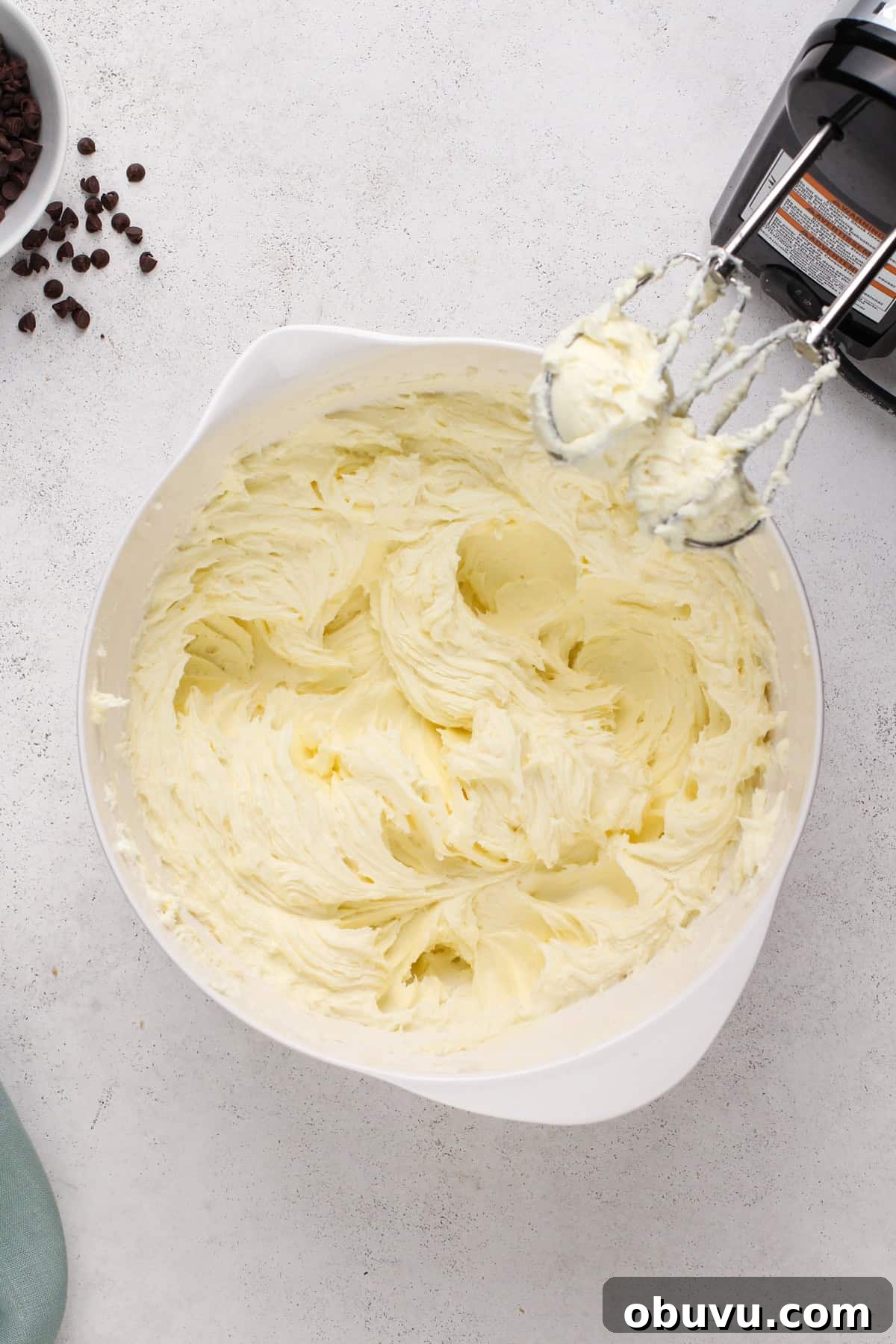 Cream cheese beaten with sugar and flour in a white bowl.