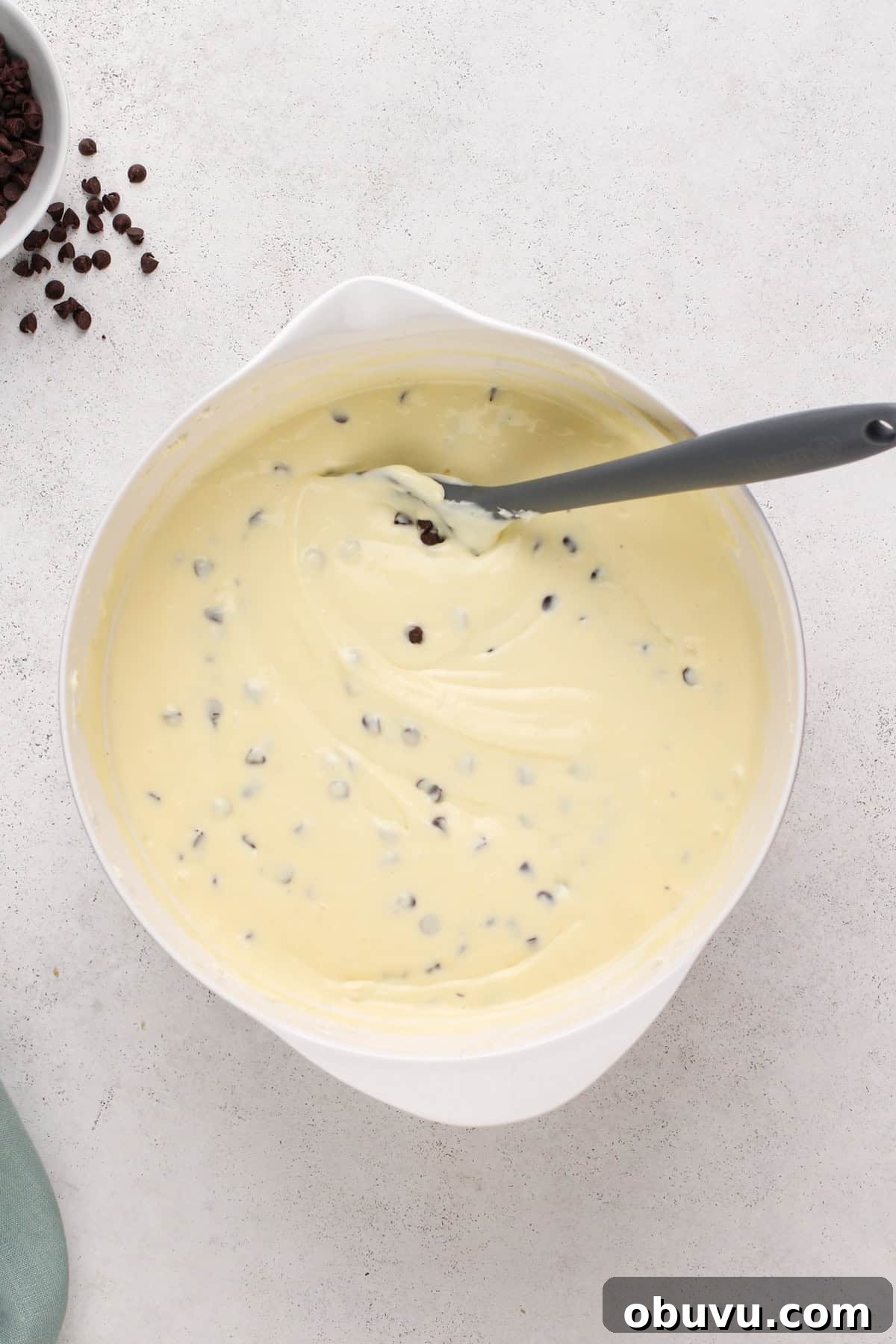 Chocolate chip cheesecake batter in a white bowl.