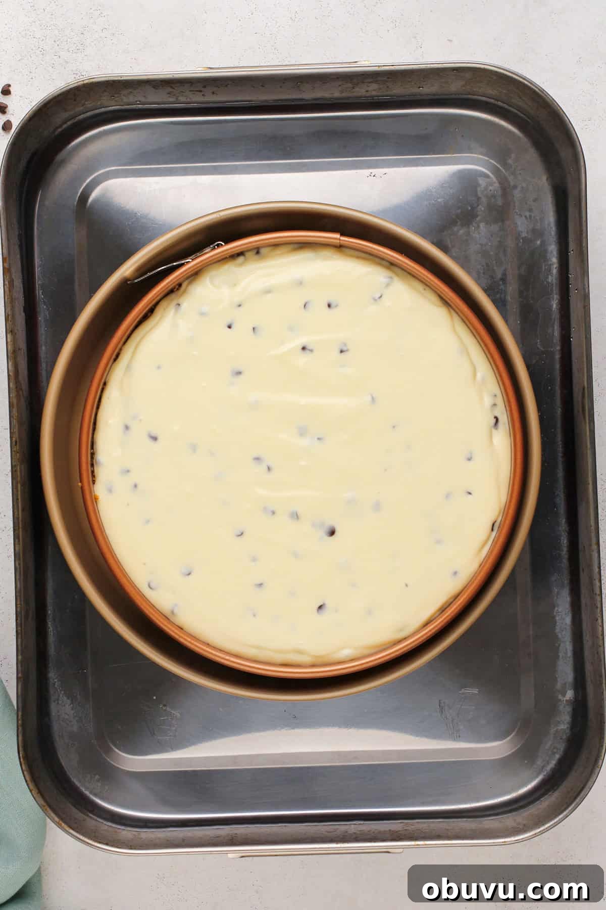 Unbaked chocolate chip cheesecake in a water bath, ready to go in the oven.