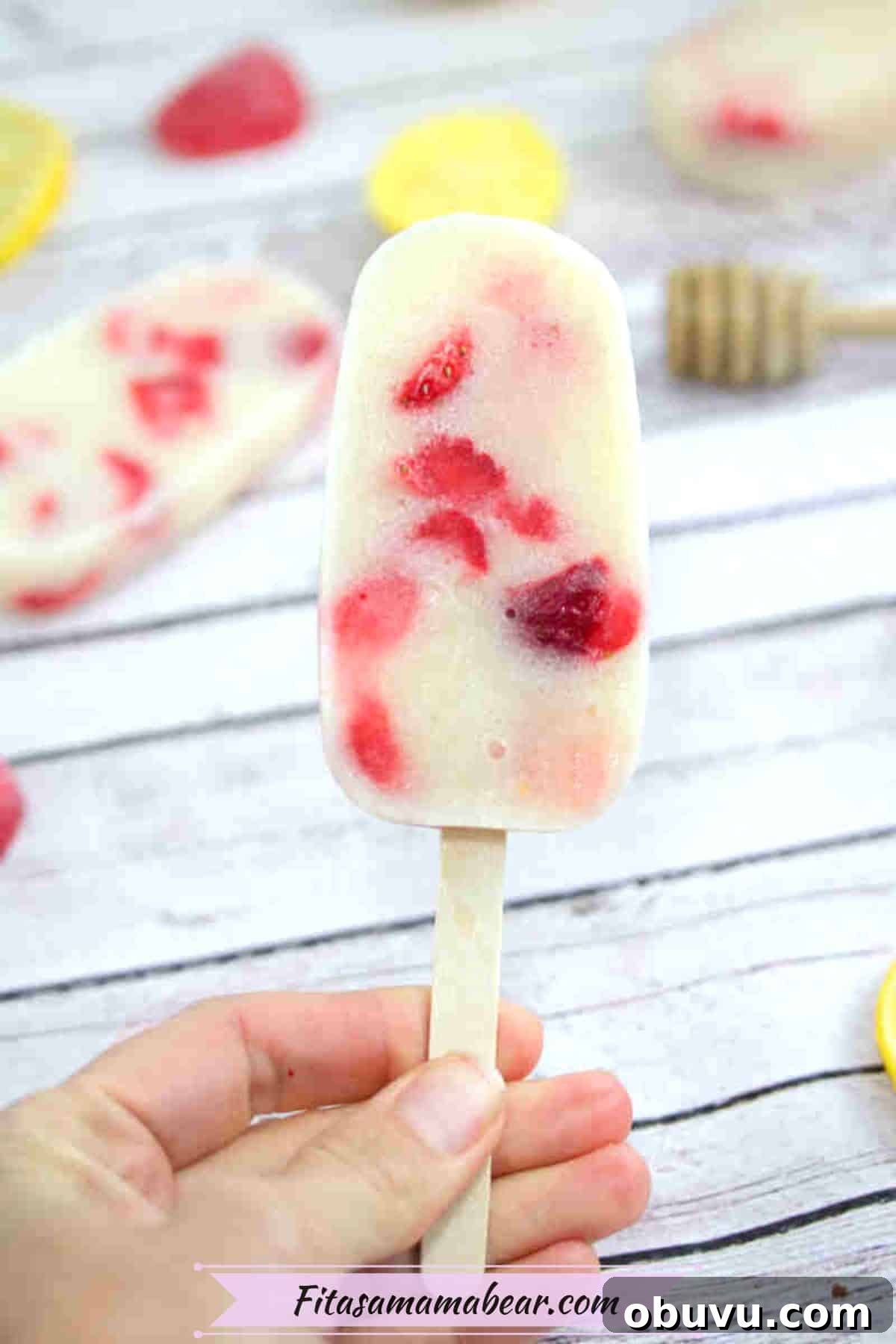 Close up of a yogurt and strawberry protein popsicle on a stick.