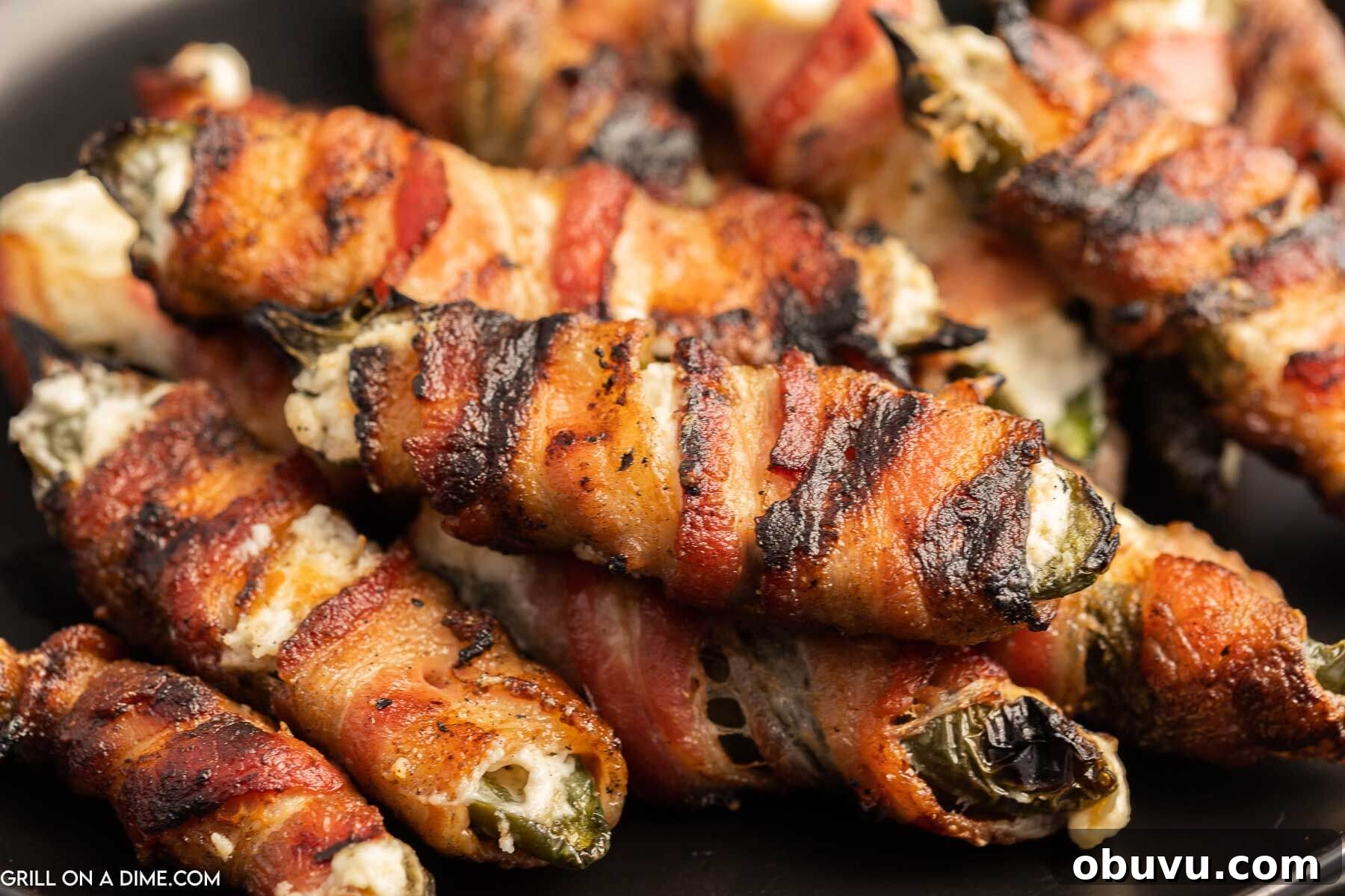 Smoky Grilled Jalapeño Poppers with Cream Cheese Filling 2 Bacon wrapped jalapeno poppers stacked on a plate