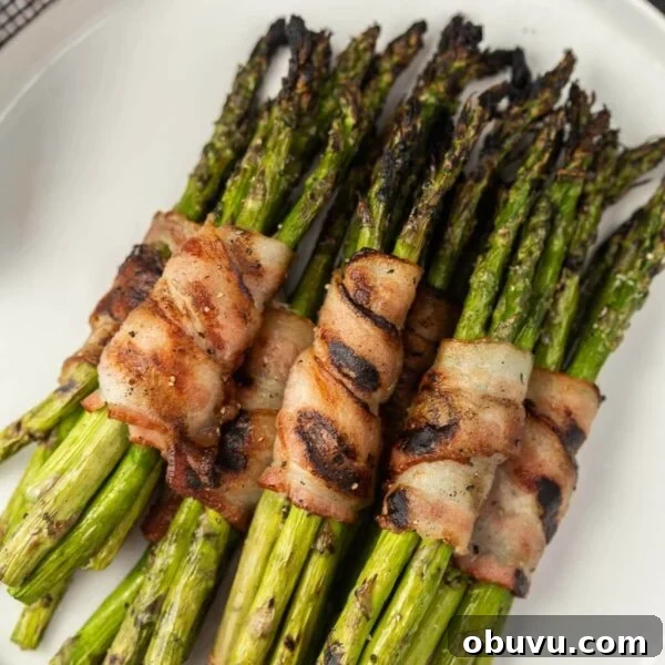 Smoky Grilled Jalapeño Poppers with Cream Cheese Filling 12 Bacon wrapped asparagus stacked on a plate