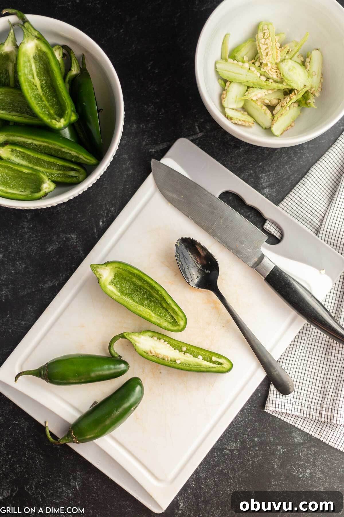 Smoky Grilled Jalapeño Poppers with Cream Cheese Filling 4 Slice Jalapenos on a cutting board with a knife and a spoon