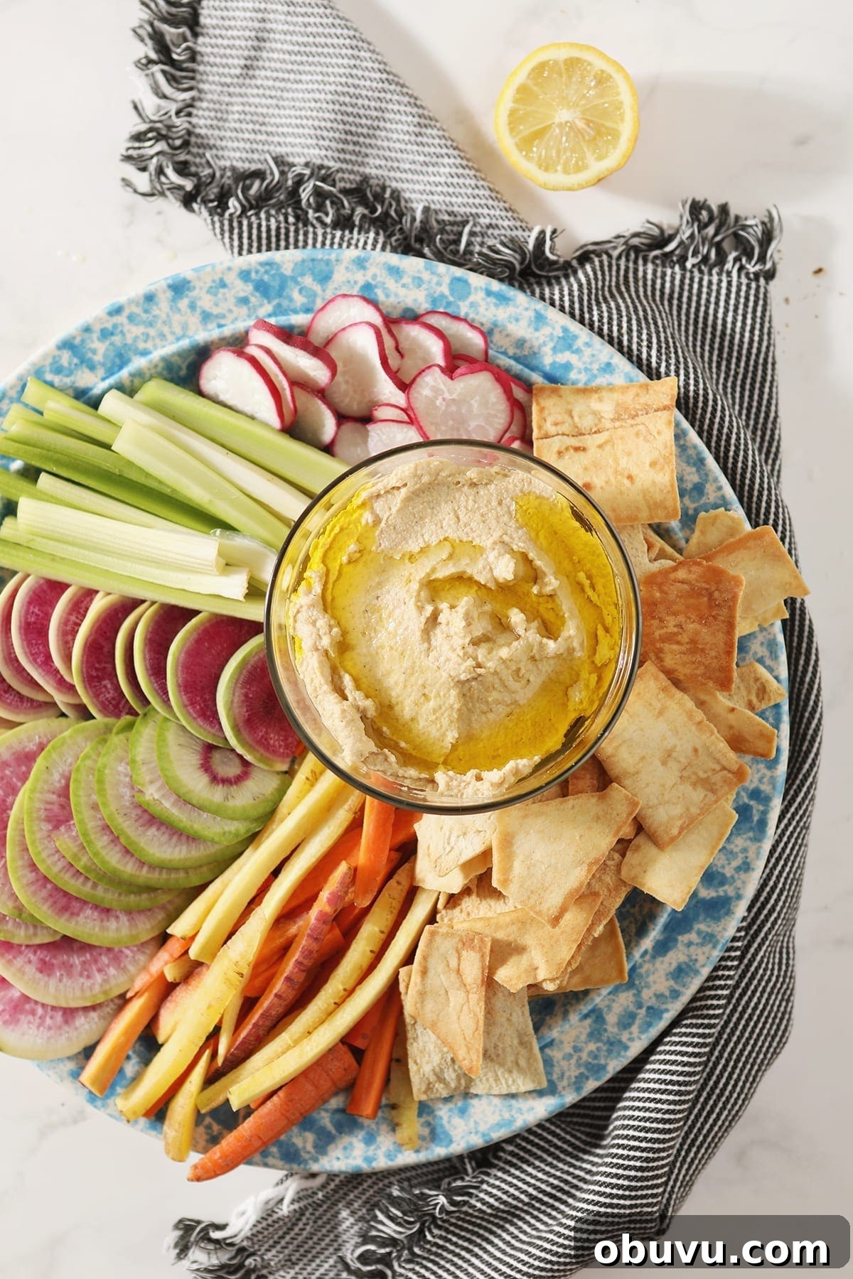 Winston’s Roasted Garlic Hummus Recipe 2 Garlic Hummus, drizzled with olive oil, sits in a glass container surrounded by radish, celery and carrot slices and pita chips