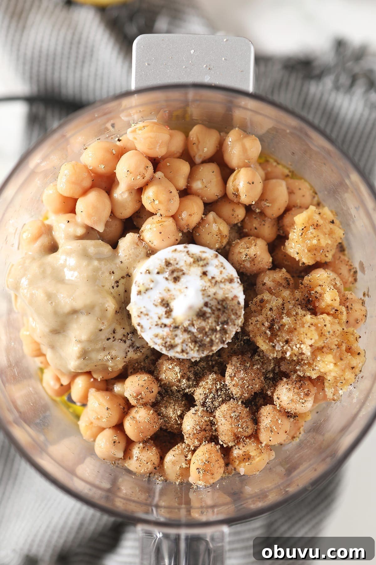 Winston’s Roasted Garlic Hummus Recipe 4 Close up of chickpeas, salt, pepper, tahini, garlic and other ingredients in a food processor before blending