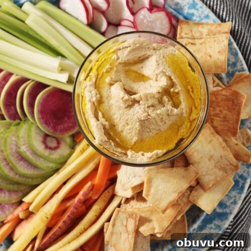 Winston’s Roasted Garlic Hummus Recipe 8 Hummus, drizzled with olive oil, sits in a glass container surrounded by radish, celery and carrot slices and pita chips