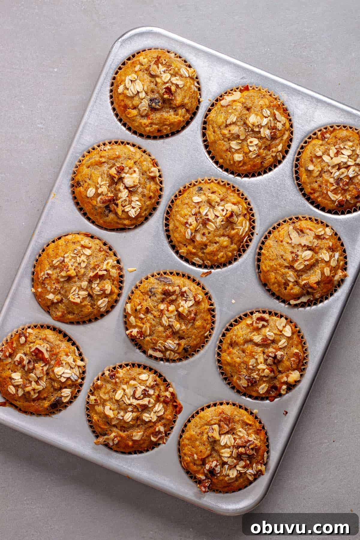 Freshly baked carrot banana muffins on a gray table.