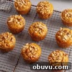 A wire rack with carrot and banana muffins cooling and a muffin tin in the background.