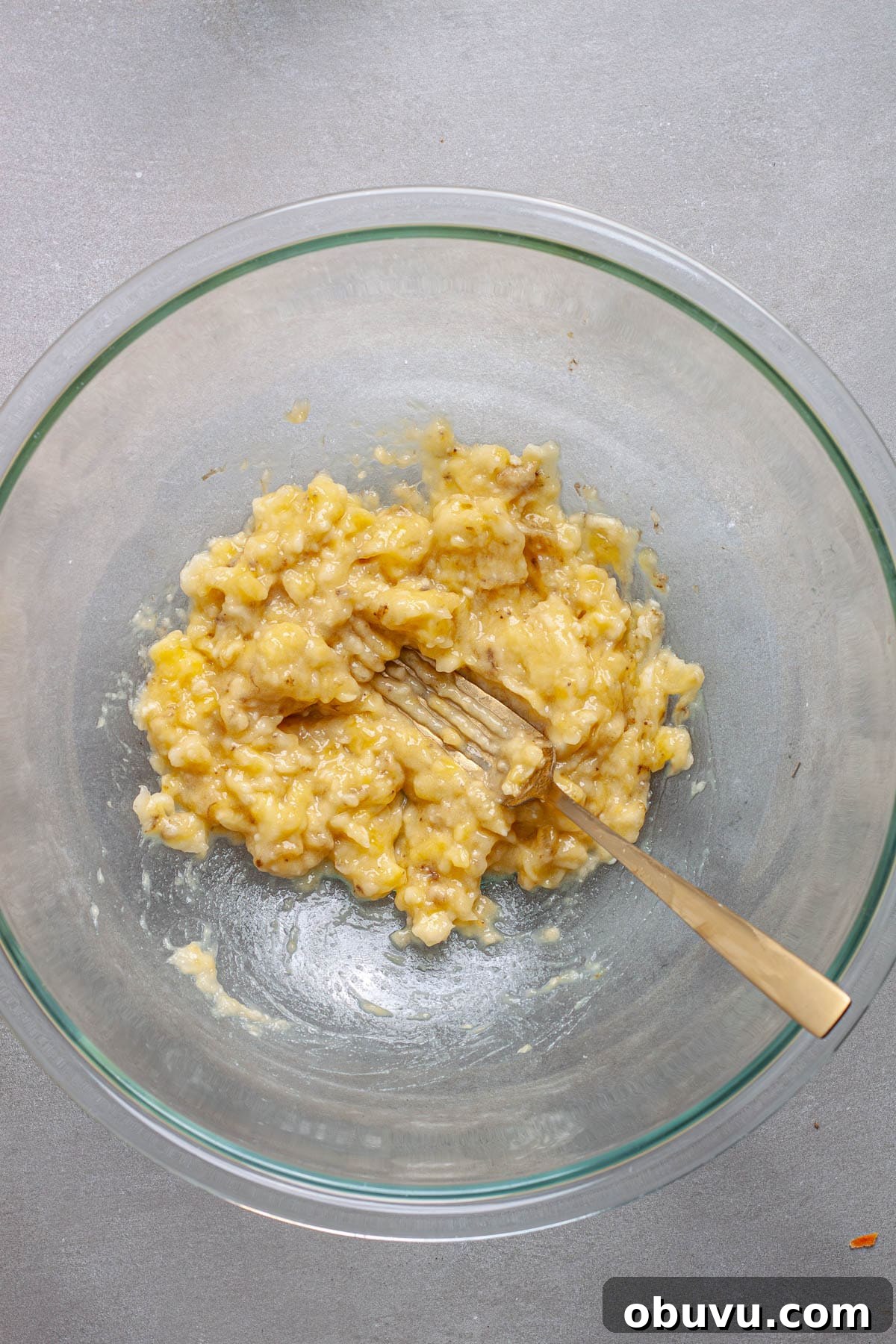 Bananas mashed in a large mixing bowl.