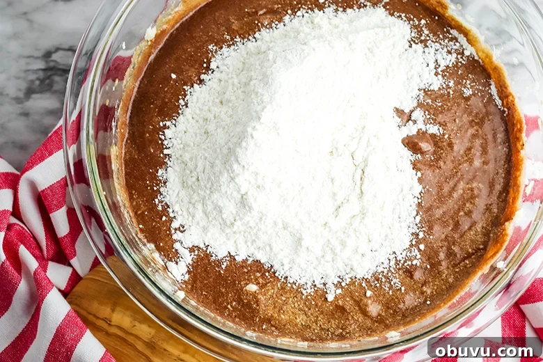 Chocolate Peppermint Pound Cake Recipe — Festive Holiday Dessert 8 Adding flour to chocolate batter in glass bowl