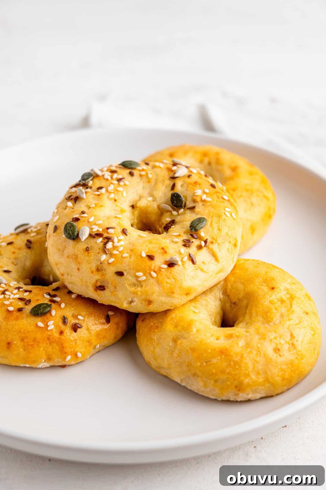 3-Ingredient Bagels Ready in 30 Minutes (No Rise) 8 Four three ingredient bagels on a white plate.