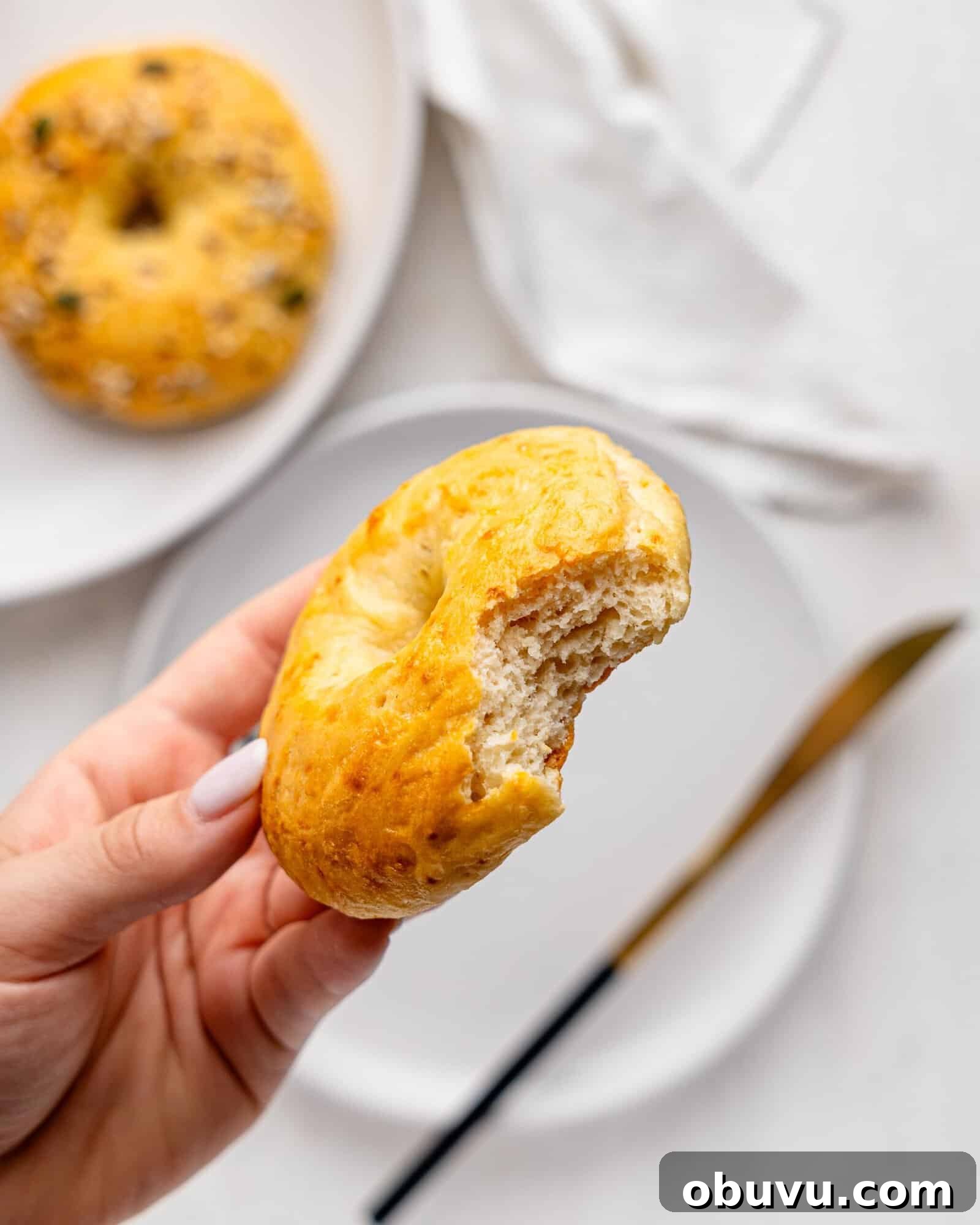 3-Ingredient Bagels Ready in 30 Minutes (No Rise) 9 A hand holding a 3 ingredient bagel with a bite missing.
