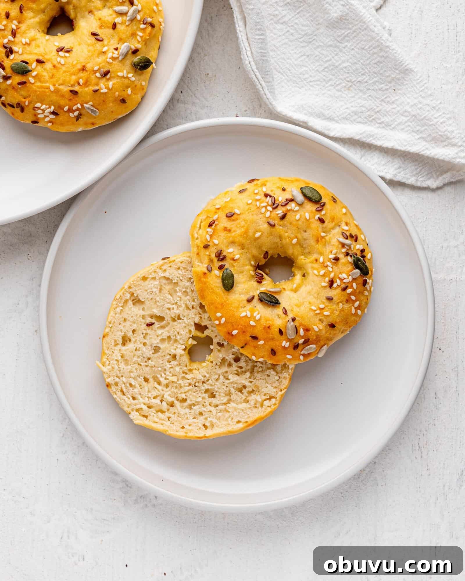 3-Ingredient Bagels Ready in 30 Minutes (No Rise) 3 A 3 ingredient bagel with seeds on a white plate.