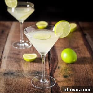 Classic Kamikaze Cocktail Recipe and Serving Tips 8 A traditional martini glass filled with a lime drink in front of a curved glass. There are limes on the side of the glasses and in them as well as on the table - square