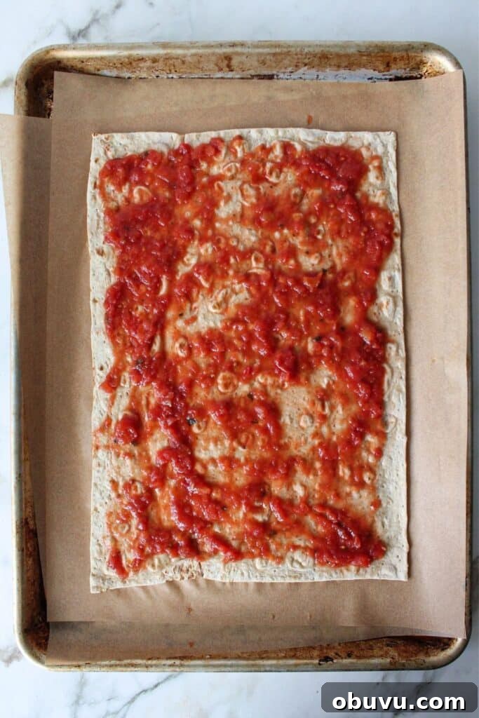High-Protein Lavash Pizza Ready in 10 Minutes 4 A process shot of lavash bread pizza with lavash bread topped with sauce.