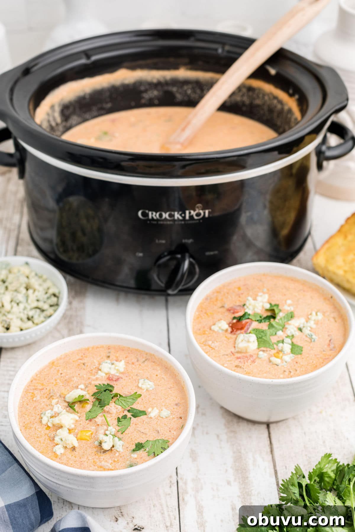 two bowls in front of a slow cooker with buffalo chicken chili dished out