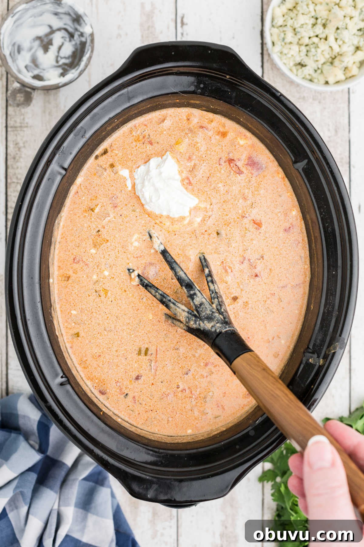 Sour cream added to a crock pot full of chili.