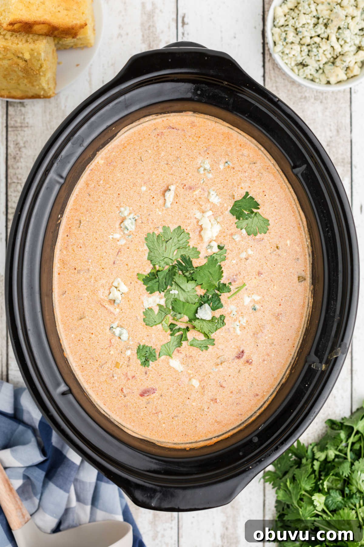 overhead shot of a slow cooker with buffalo chicken chili, with blue cheese and cilantro sprinkled on top