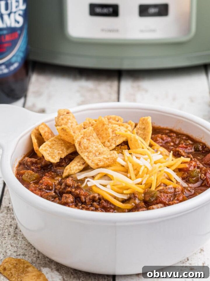 Close up side view of a bowl of beer chili with a crock pot in the background.
