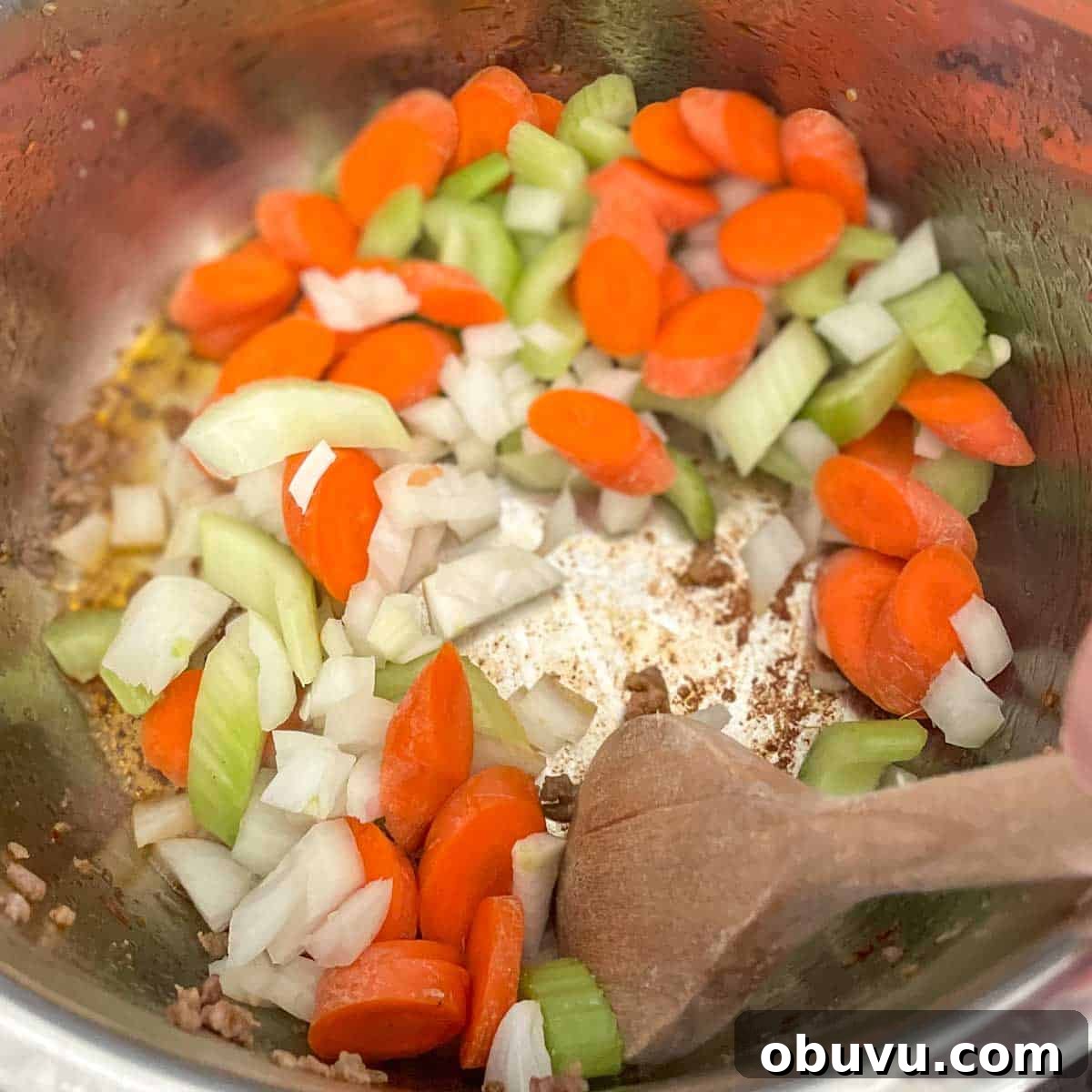 Carrot, celery, and onion are stirred in the Instant Pot.