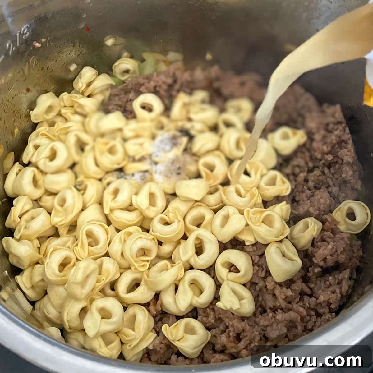 Tortellini, seasonings, sausage, and broth is added to the soup ingredients.