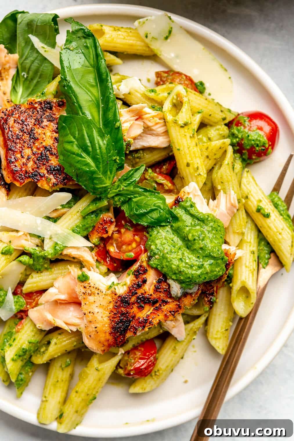 Salmon Pesto Pasta Recipe: Creamy 20-Minute Meal 2 A plate of salmon pesto pasta topped with basil leaves and shredded parmesan cheese.