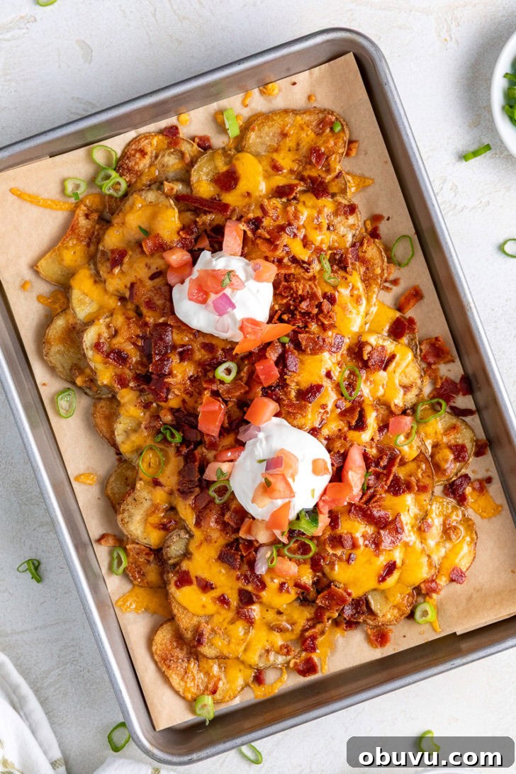 Loaded Potato Nachos with Cheese, Jalapeño & Sour Cream 3 Overhead shot of crispy potatoes with cheese, bacon, sour cream, and green onions.