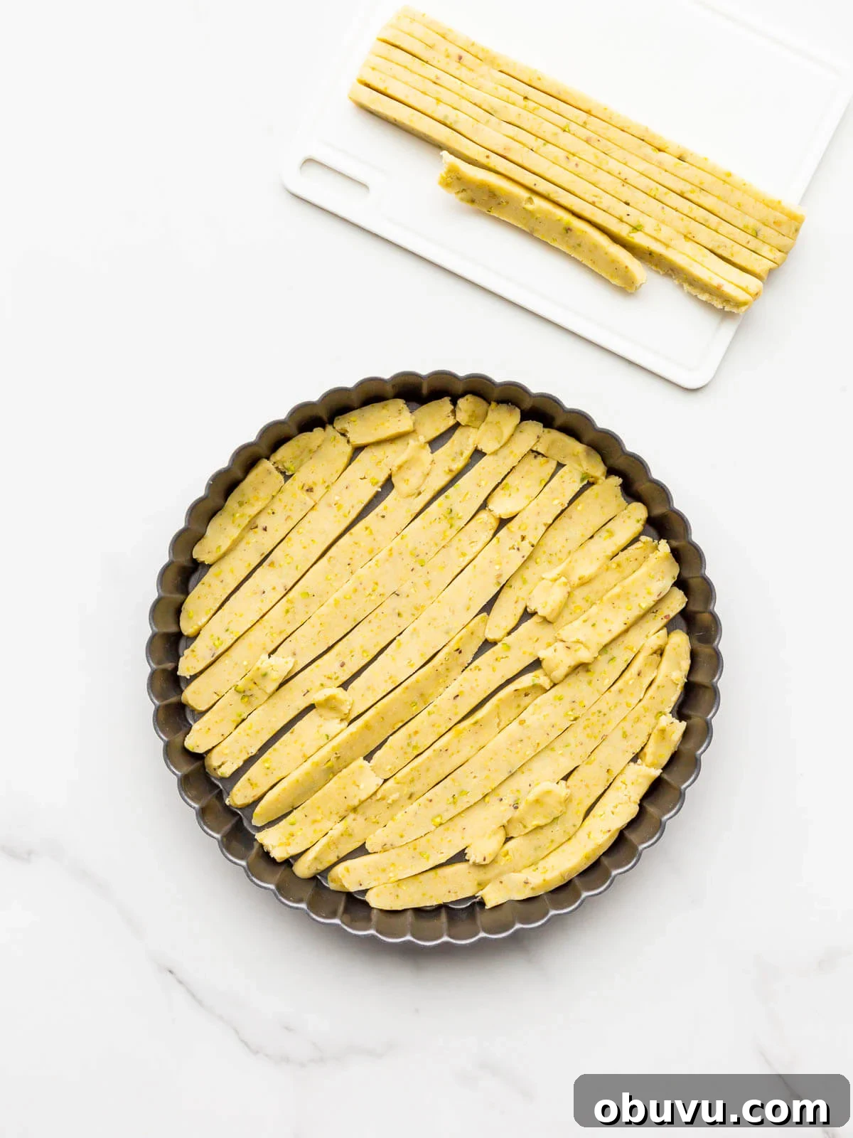 Lining tart pan with thin slices of unbaked sweet dough to make a tart shell.