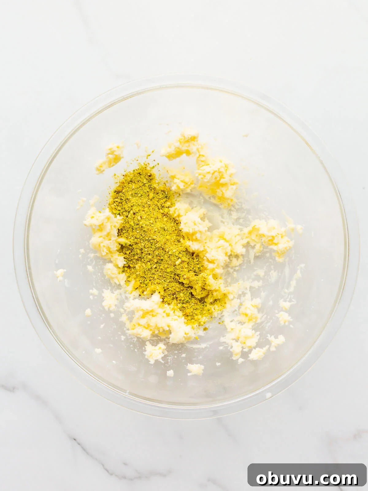Adding ground pistachios to a bowl to make a sweet pistachio tart crust.