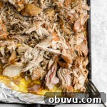 Tender Sous Vide Pork Shoulder Recipe for Juicy, Fall-Apart Meat 11 A foil-lined sheet pan full of shredded sous vide pork with a fork on the side.