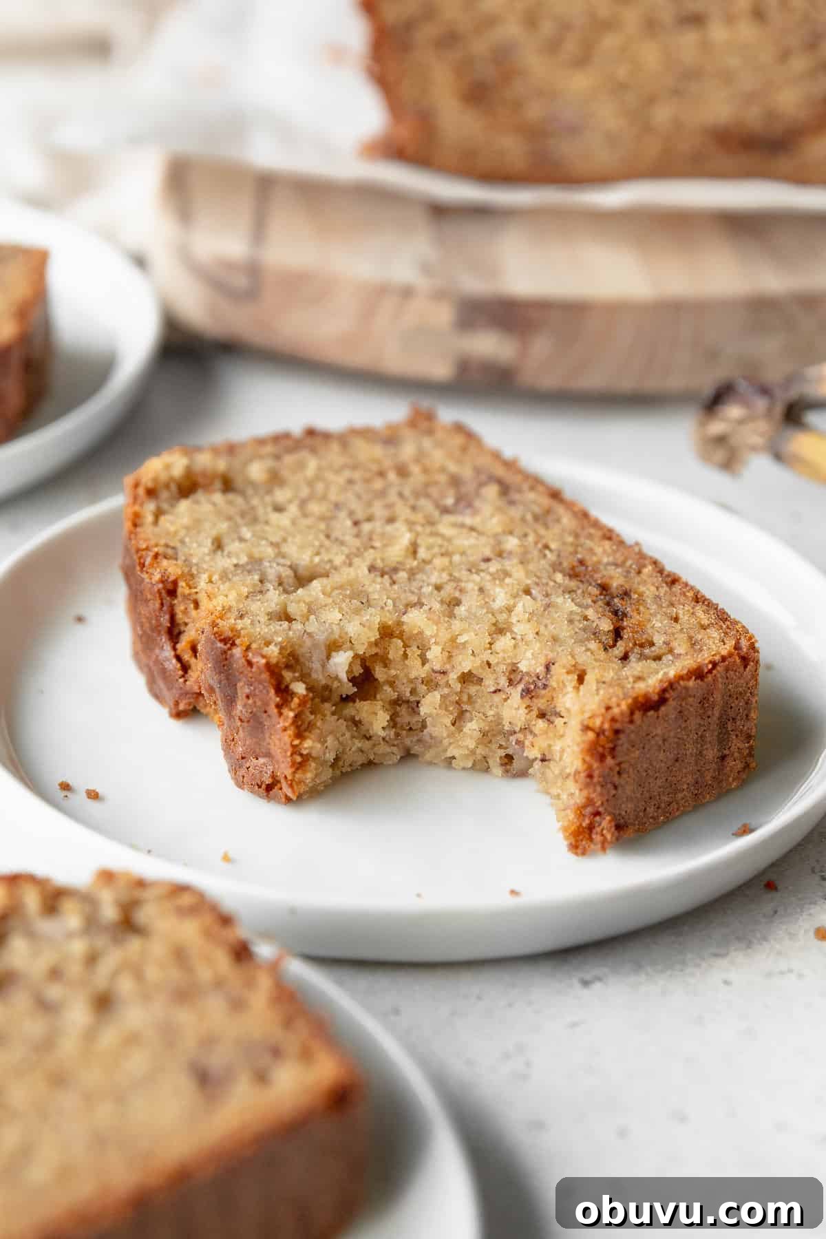 Moist Banana Bread Without Gluten — Simple Recipe for Tasty Loaf 10 A bitten slice of gluten free banana bread on a small white plate.