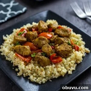 Keto Pork Curry with Cauliflower Rice Bowl 7 Cooked and cubed pork curry over steamed cauliflower rice on a square black plate.