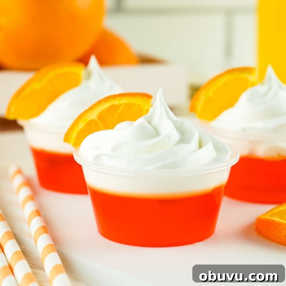 Mimosa Jello Shots Recipe: Sparkling Champagne Party Treat 2 three mimosa jello shots with whipped cream and an orange slice for garnish