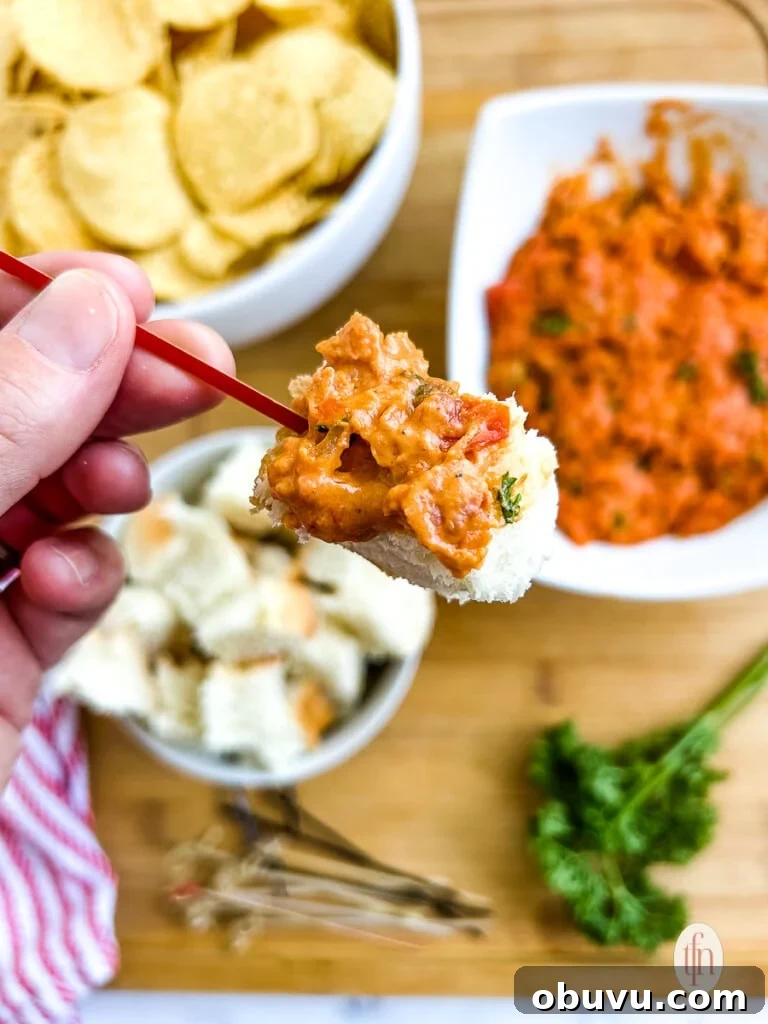 Large cube of bread on a toothpick, covered in smoked queso with chorizo.